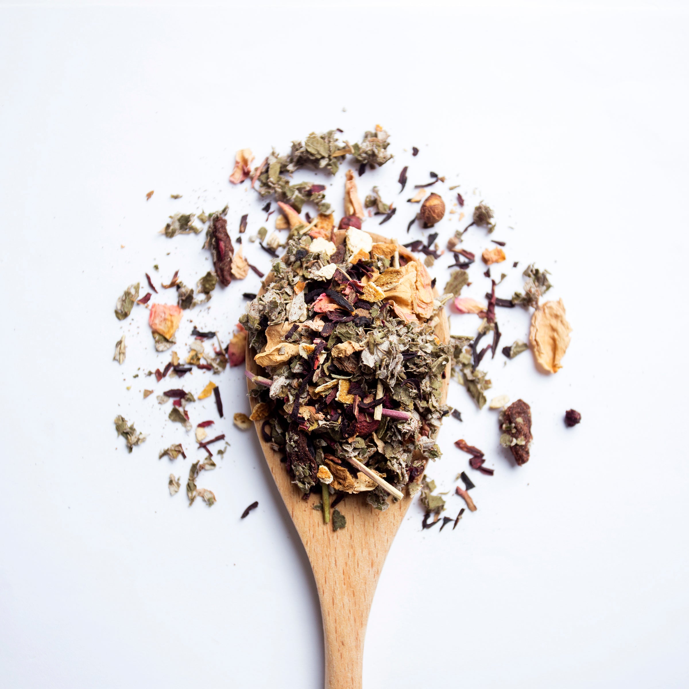 Organic herbal Acai Berry Wellness tea blend with acai berries and dried fruit pieces on wooden spoon