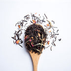 Organic herbal Herbal Sunrise tea blend with Ceylon and Assam black tea, white tea and rose petals on wooden spoon