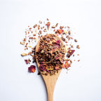 Organic herbal Digestive Harmony tea blend with flaxseed, rose petals and herbs on wooden spoon