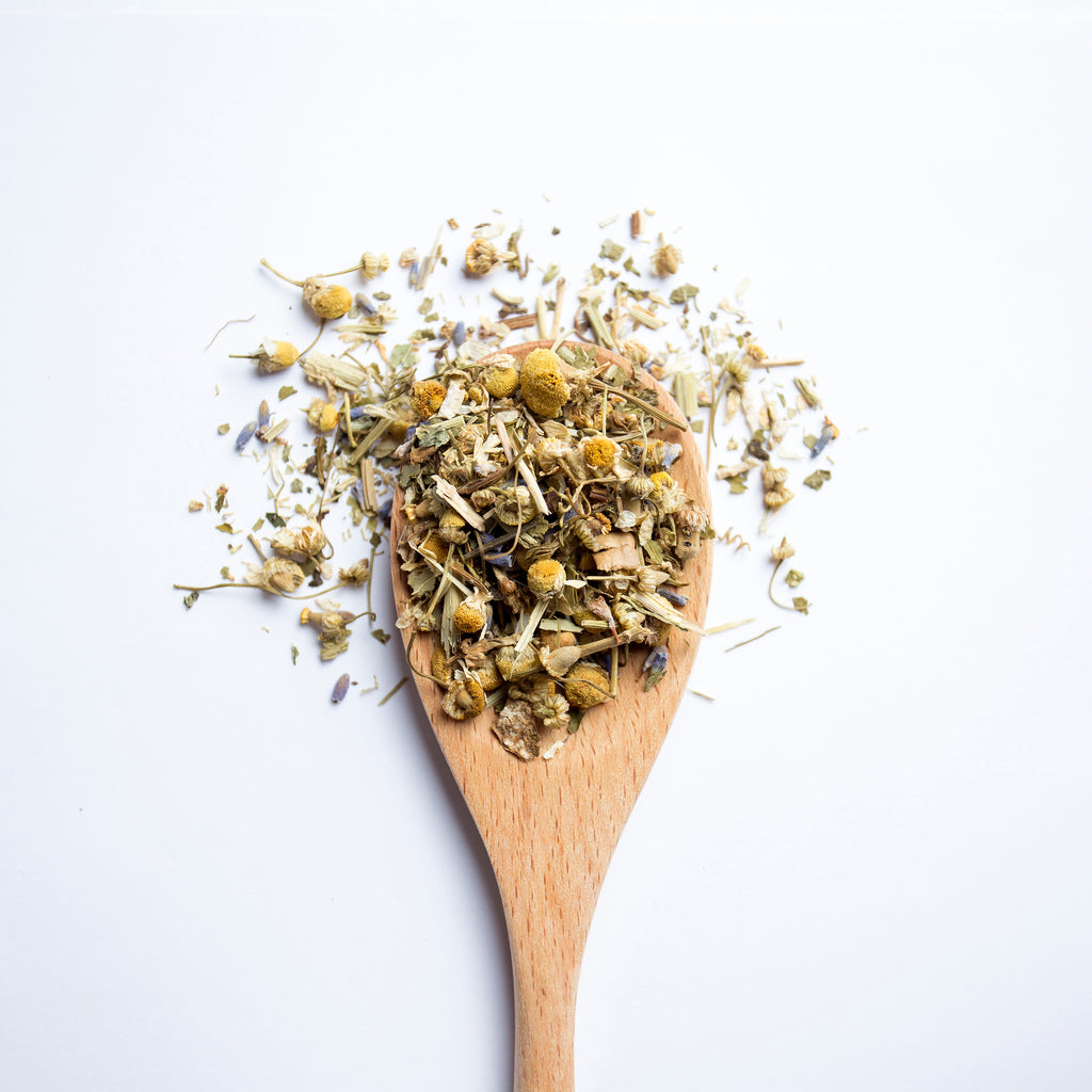 Organic herbal Sleepy Garden tea blend with chamomile flowers and herbs on wooden spoon
