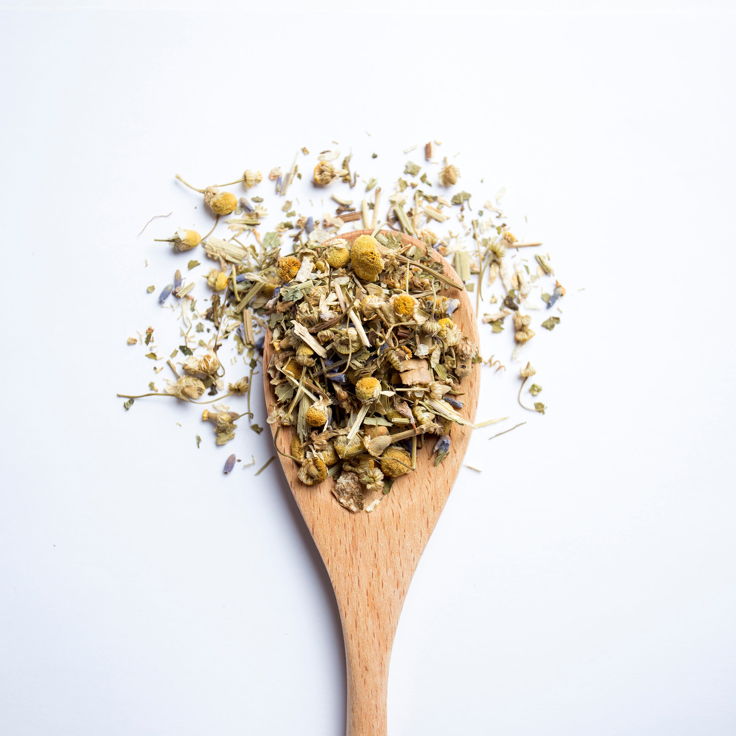 Organic herbal Sleepy Garden tea blend with chamomile flowers and herbs on wooden spoon