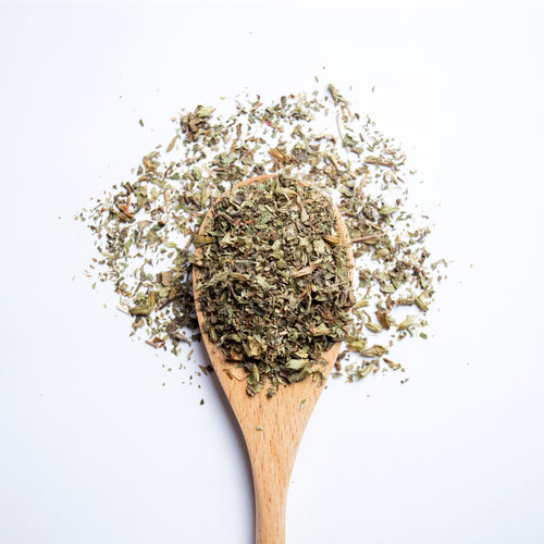 Organic herbal Relax & Unwind tea blend with lemon balm, ashwagandha, peppermint and ginger on wooden spoon